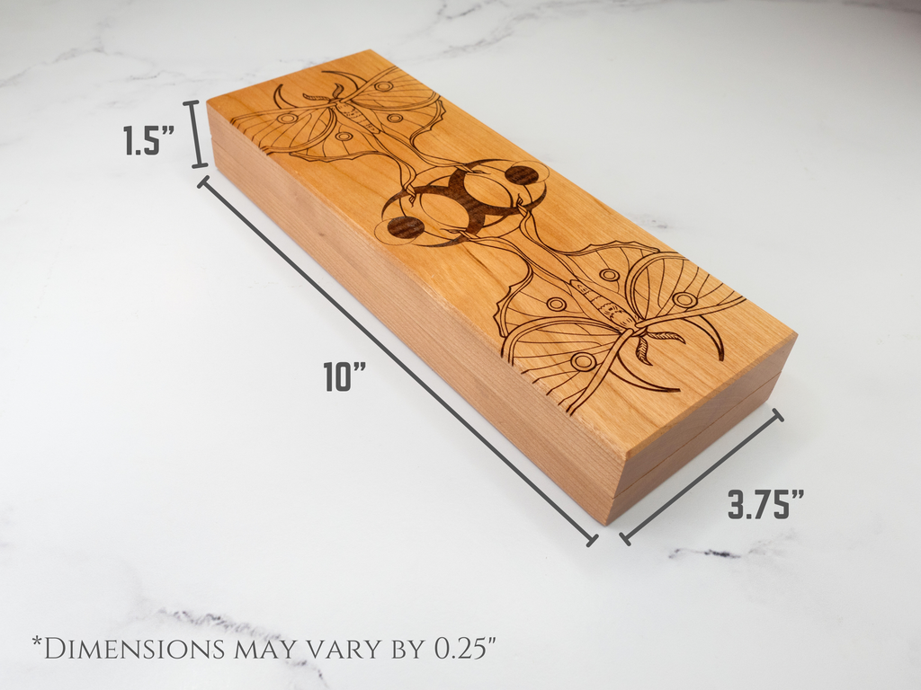 Wooden dice vault with engraved design and measurements on a marble surface