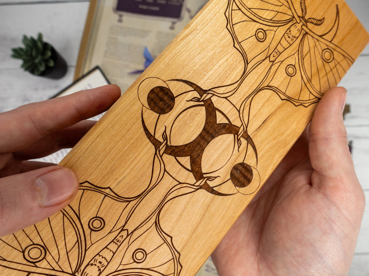 Wooden dice vault with engraved abstract fantasy design held by a hand on a light background