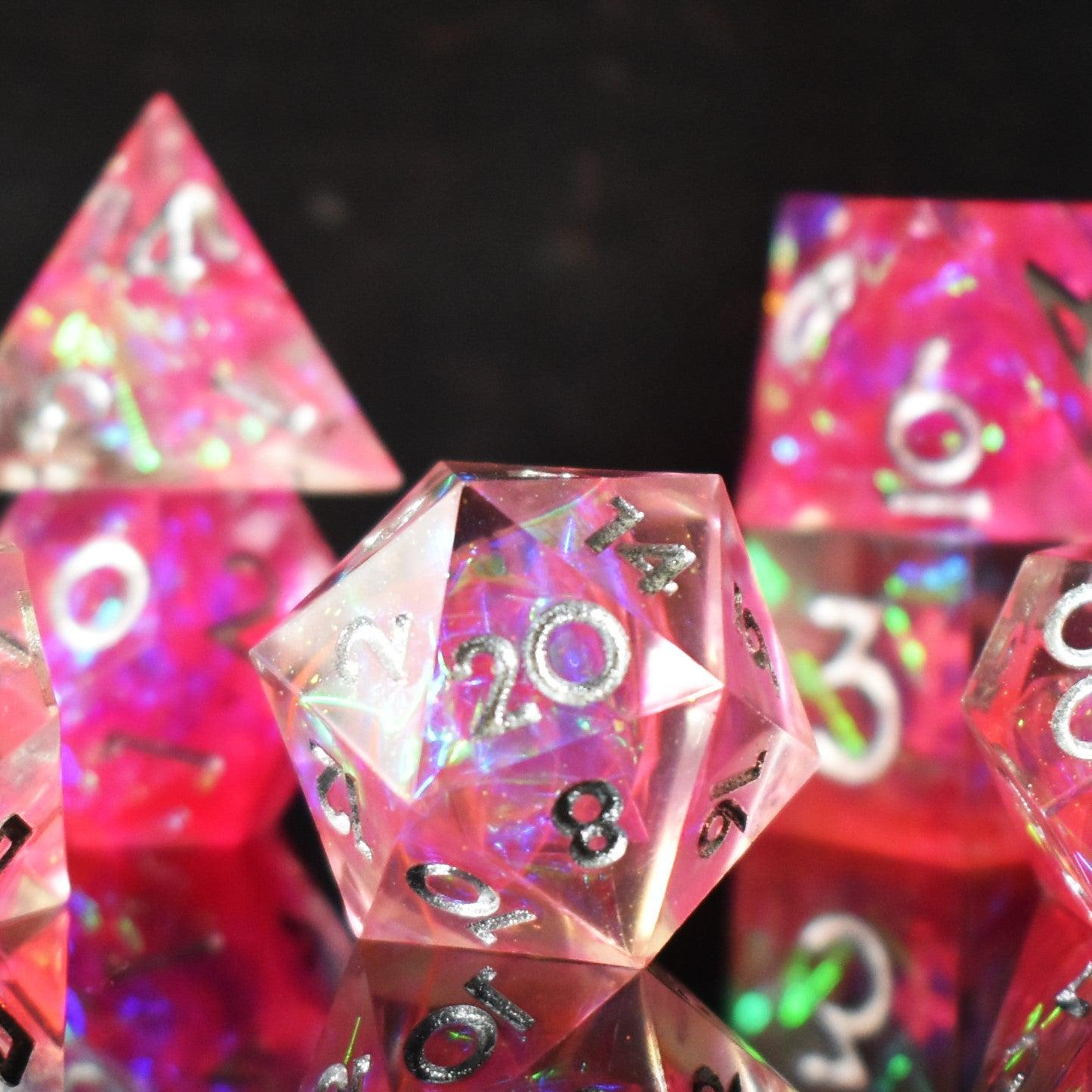 A set of sharp-edged, pink resin dnd dice with silver engraved numbers, reflecting a metallic sheen inside of each die