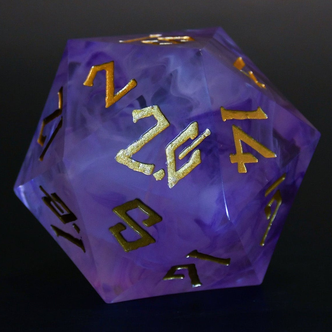 A 50mm purple resin dice with gold engraved numbers, on a dark background.