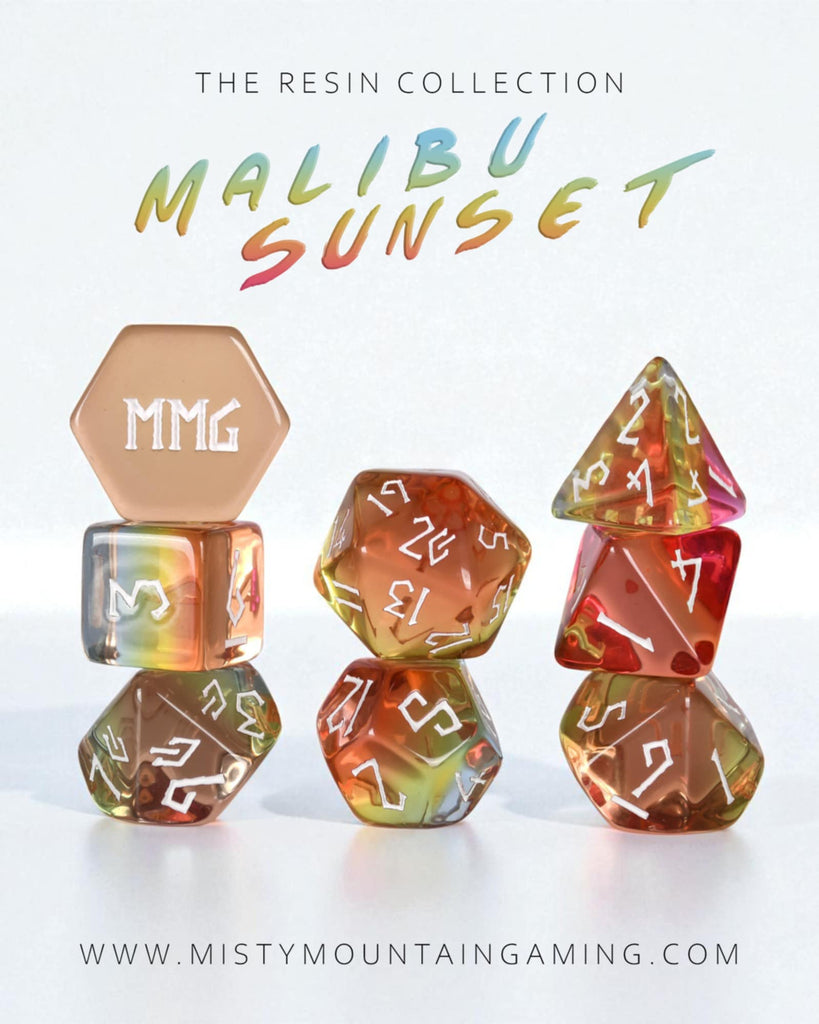 Set of colorful polyhedral dice with 'MMG' branding on a white background, featuring the text 'The Resin Collection Malibu Sunset' and website 'www.mistymountaingaming.