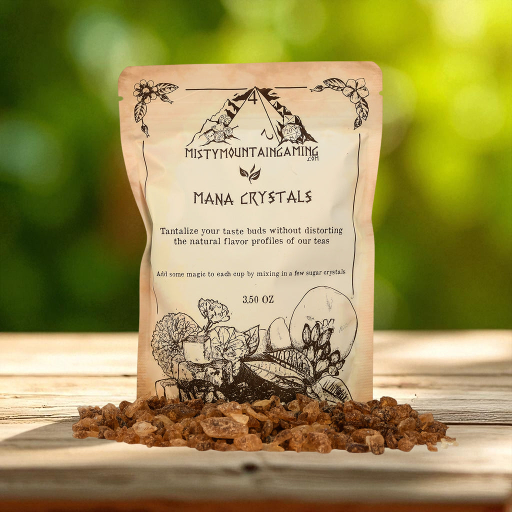 Bag of 'Mana Crystals' from Misty Mountain Gaming for tea on a wooden surface with a blurred natural background.