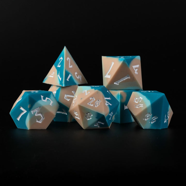 A set of silicone dice with blue and beige colors, featuring engraved numbers, displayed on a dark background.