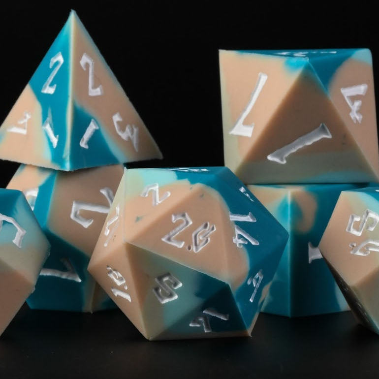 A set of silicone dice with blue and beige colors, featuring engraved numbers, displayed on a dark background.