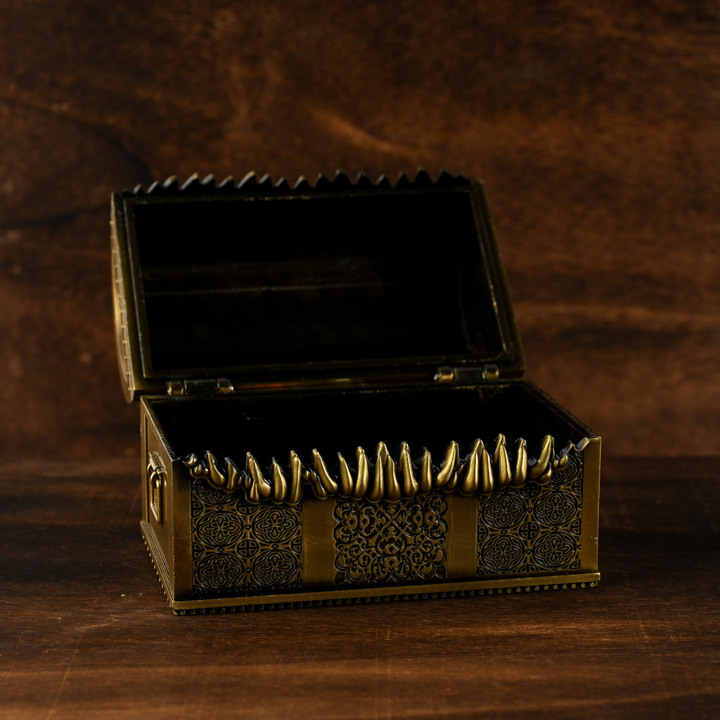 A gold-colored metal mimic chest filled with multicolored dice, set against a wooden background.
