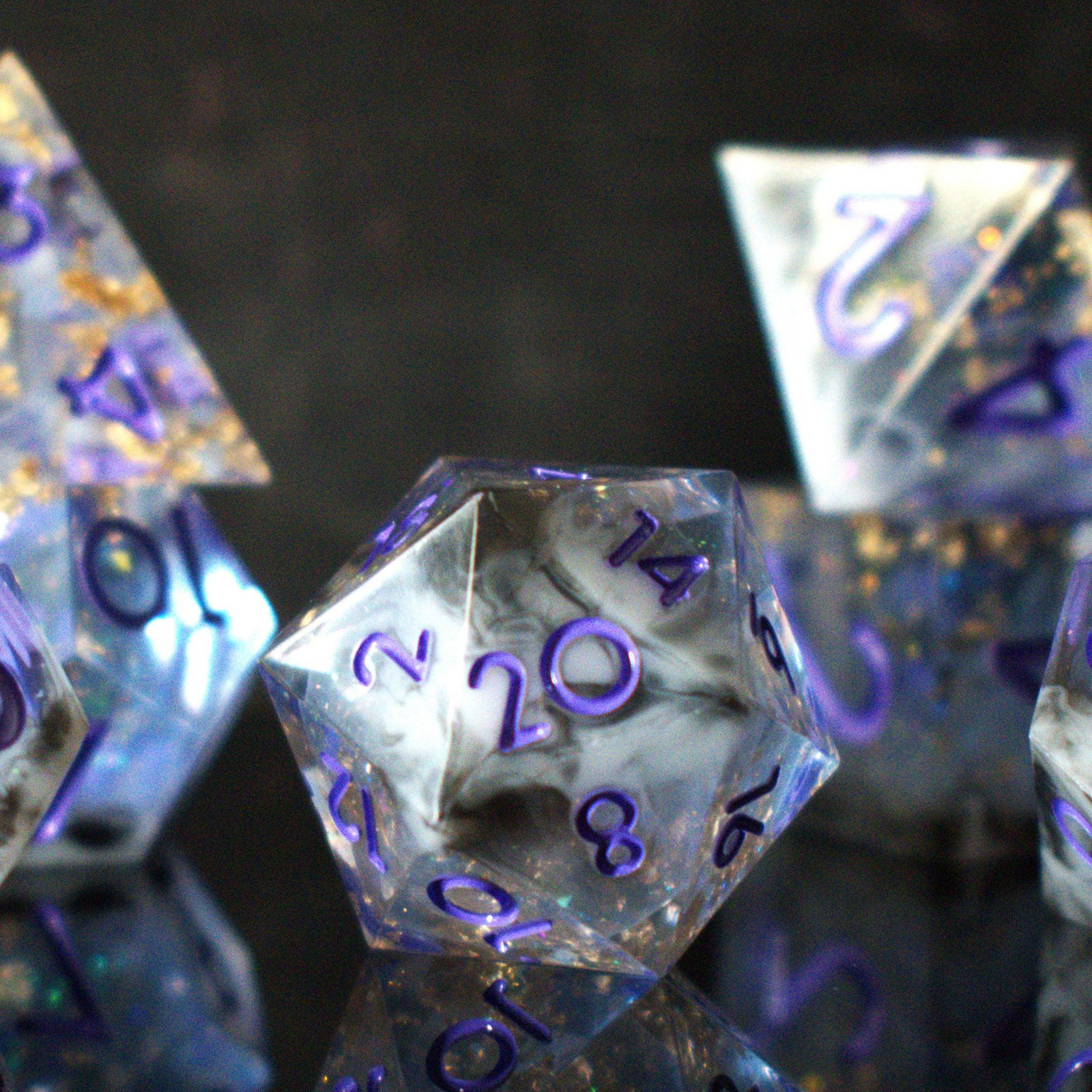 A clear, glittery sharp edge resin dnd dice set with cloudy white and black running through them and purple numbering for tabletop gaming