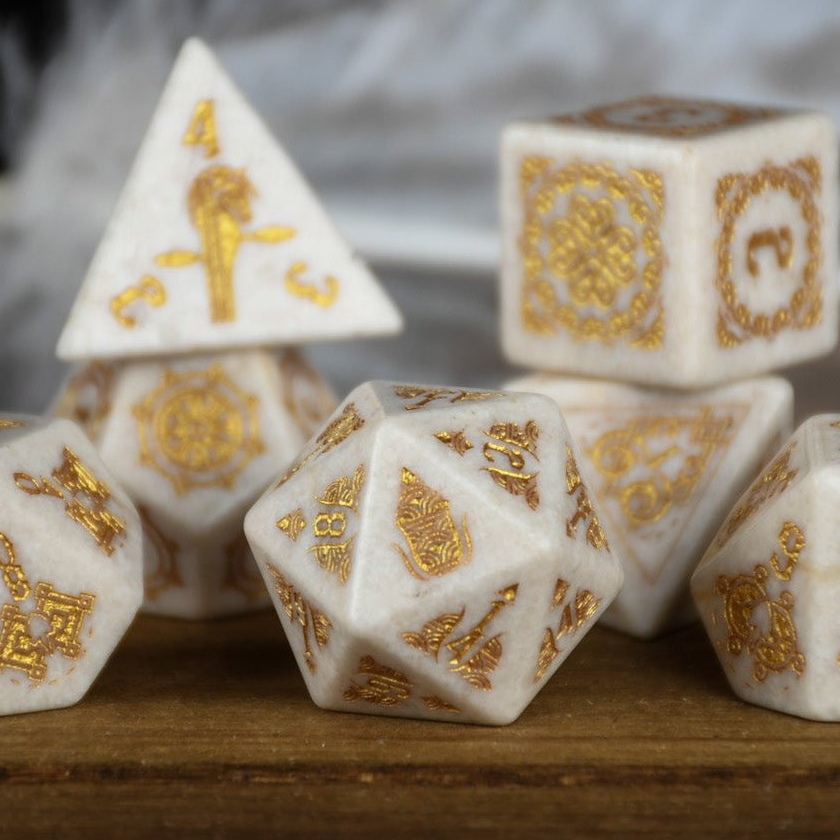 White dice with gold patterns on a wooden surface
