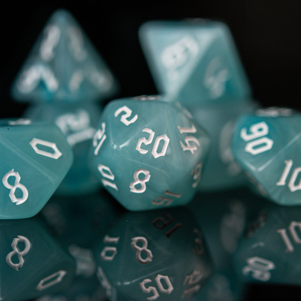 A set of teal blue acrylic dice with white numbers, including various shapes typical for role-playing games.