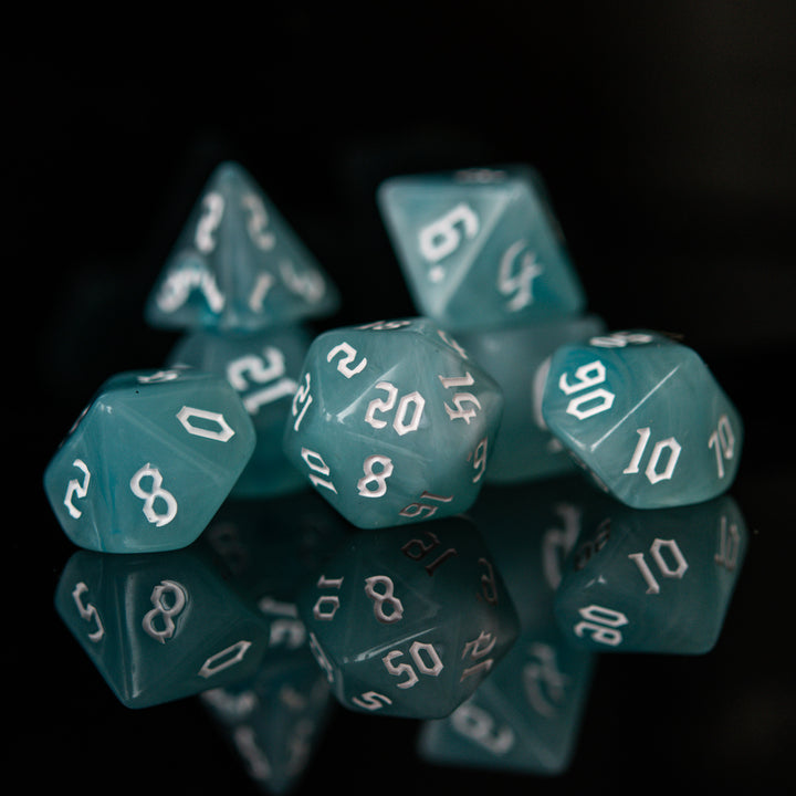 A set of teal blue acrylic dice with white numbers, including various shapes typical for role-playing games.