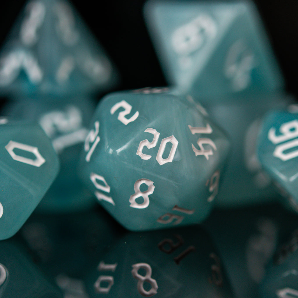 A set of teal blue acrylic dice with white numbers, including various shapes typical for role-playing games.