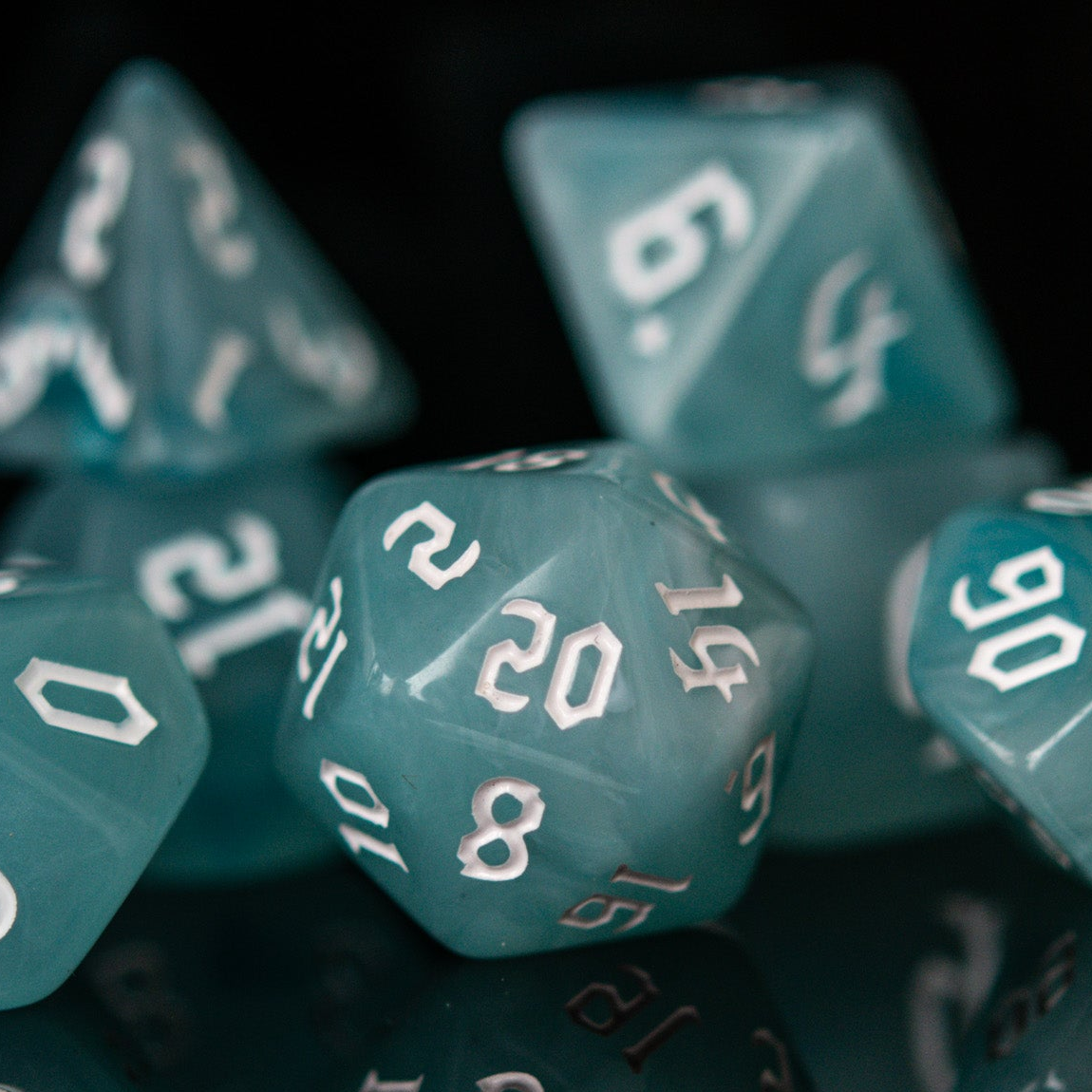 A set of teal blue acrylic dice with white numbers, including various shapes typical for role-playing games.