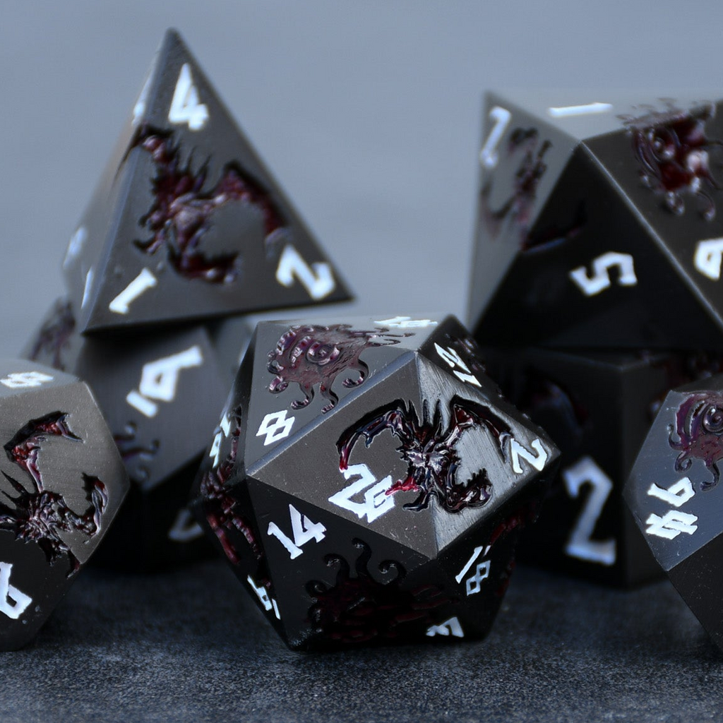 A set of metal dice in gunmetal and crimson color with engraved dragons and beholders in crimson read and white numbers 