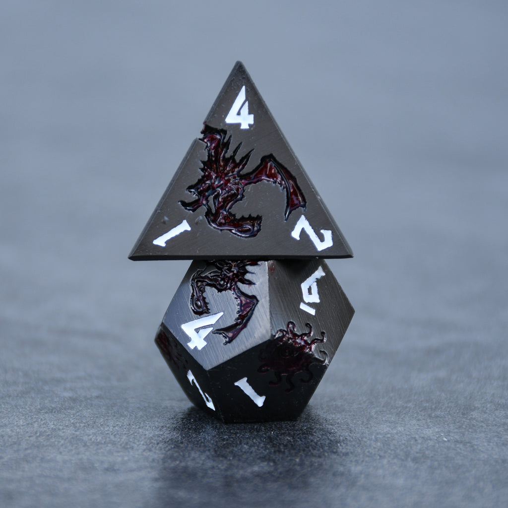 A set of metal dice in gunmetal and crimson color with engraved dragons and beholders in crimson read and white numbers 