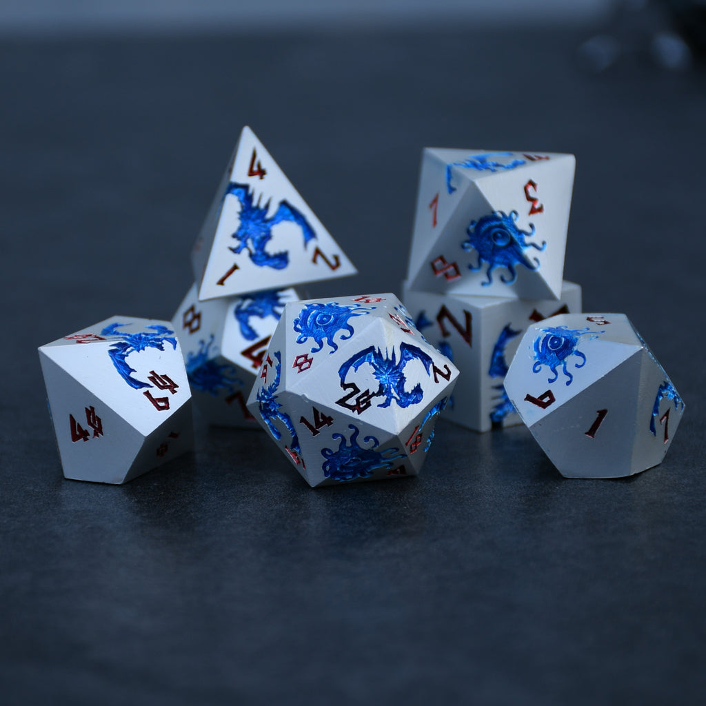 A set of silver metal dnd dice with blue monster patterns on them and red numbering