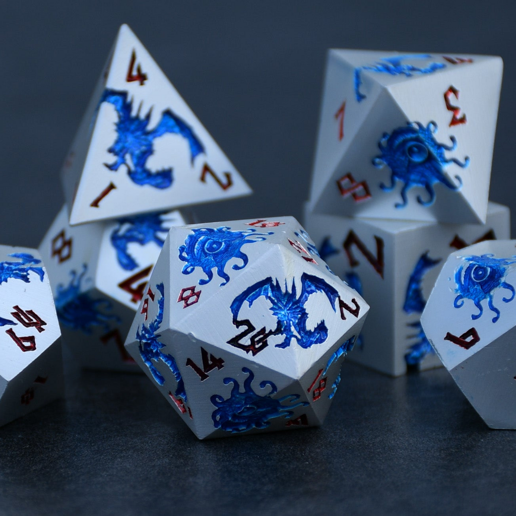 A set of silver metal dnd dice with blue monster patterns on them and red numbering