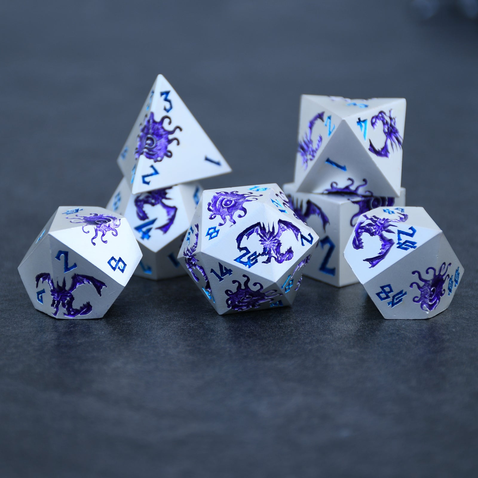 A set of silver metal dnd dice with purple monster patterns on them and blue numbering