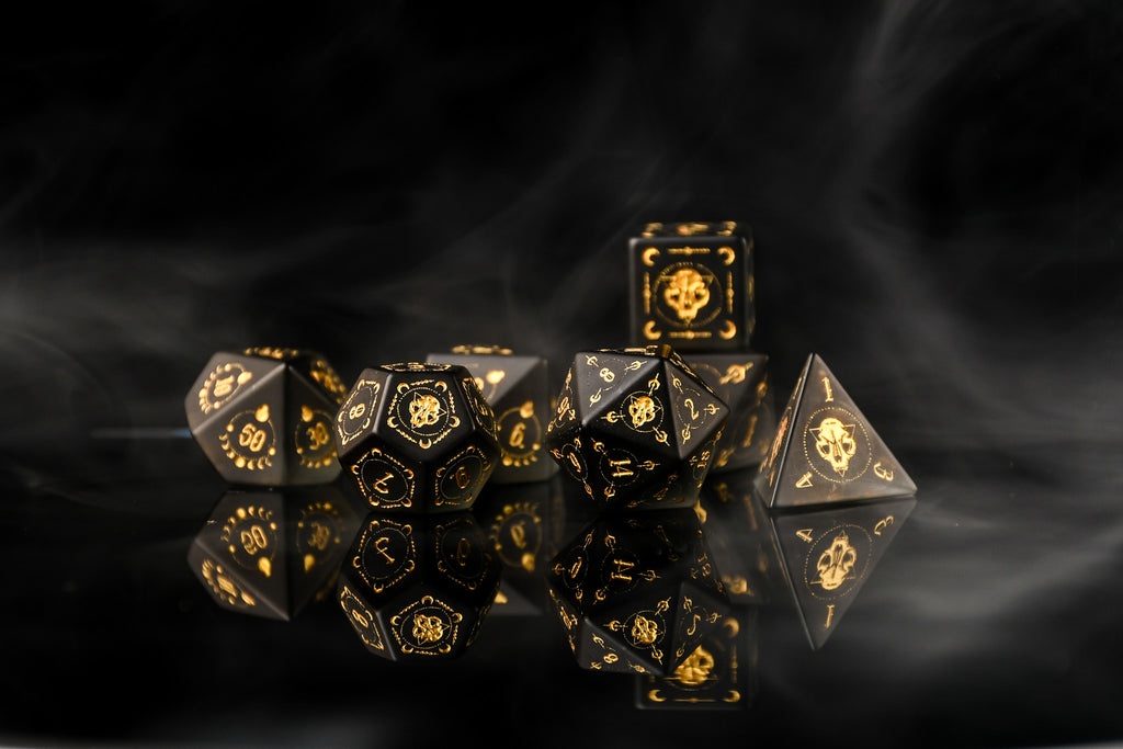 Set of black and gold polyhedral dice on a dark background