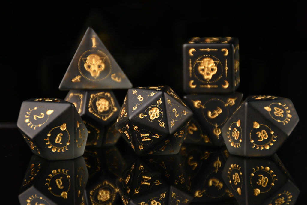 Black dice set with gold numbering and symbols on a reflective black surface