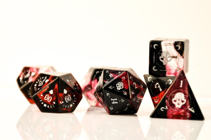 Set of black and red dice with skull designs on a white background