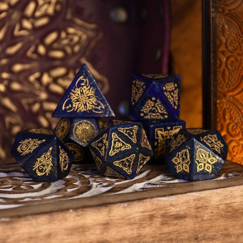 A set of hand-carved blue lapis stone dice with golden patterns, displayed on a wooden surface.