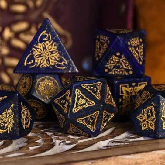 Blue polyhedral dice with gold patterns on a wooden surface