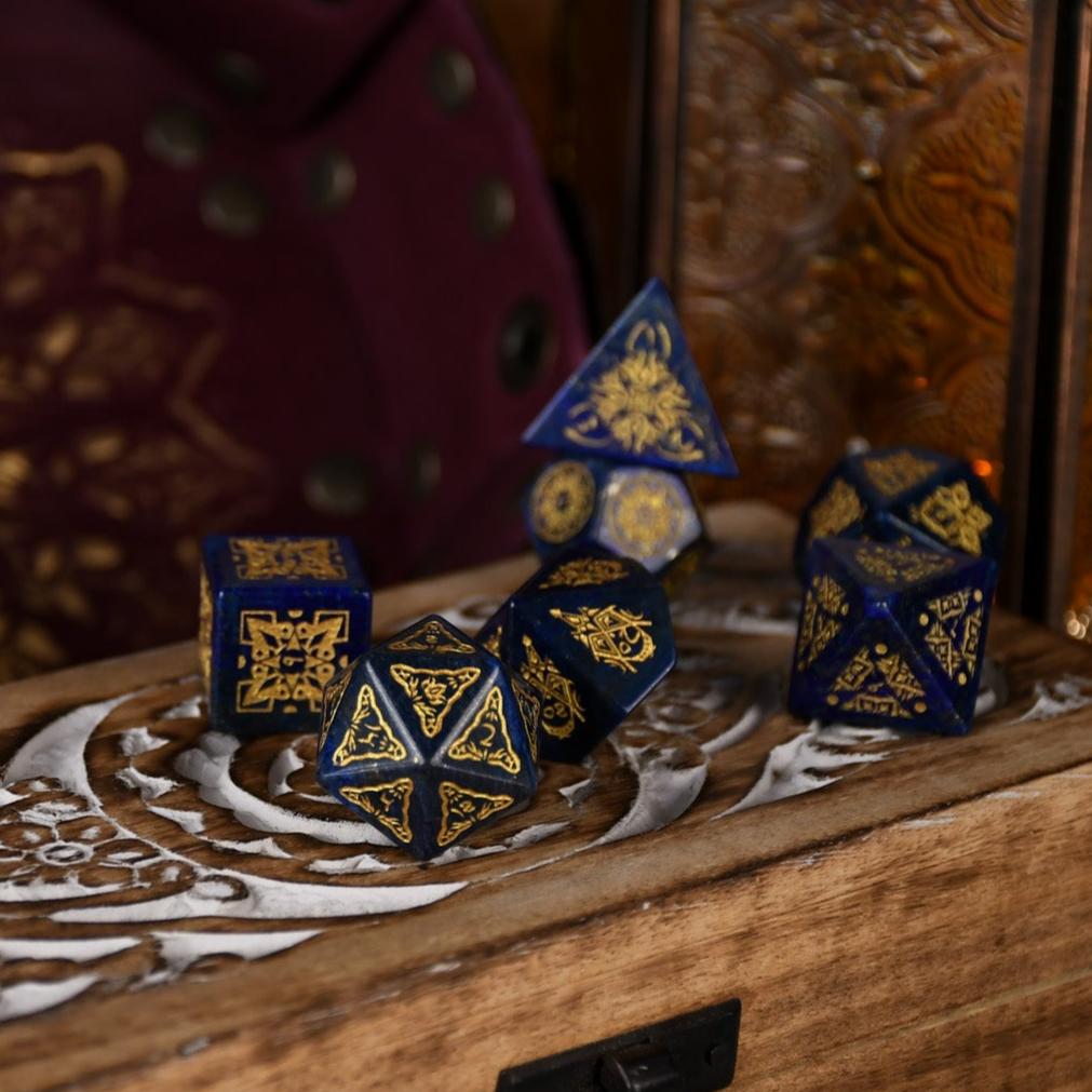 A set of hand-carved blue lapis stone dice with golden patterns, displayed on a wooden surface.