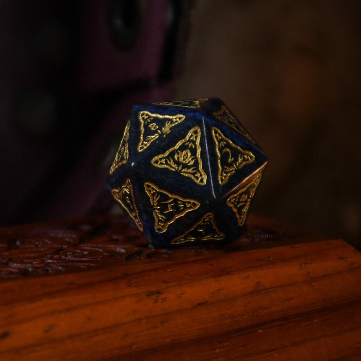A set of hand-carved blue lapis stone dice with golden patterns, displayed on a wooden surface.