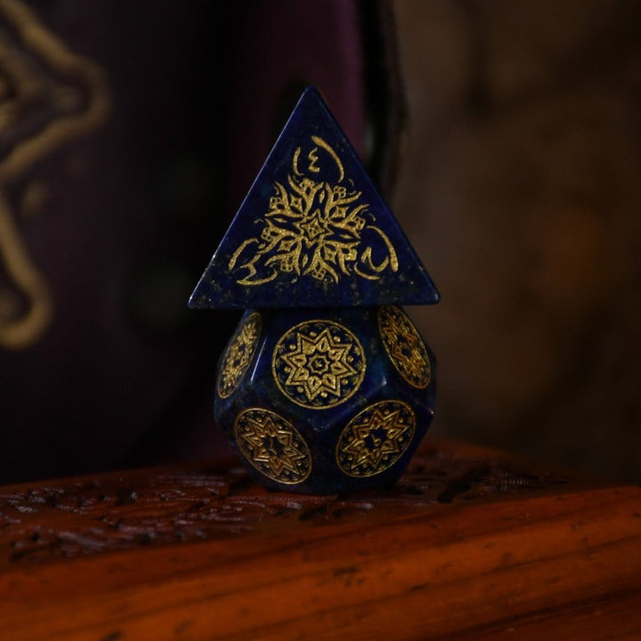 A set of hand-carved blue lapis stone dice with golden patterns, displayed on a wooden surface.