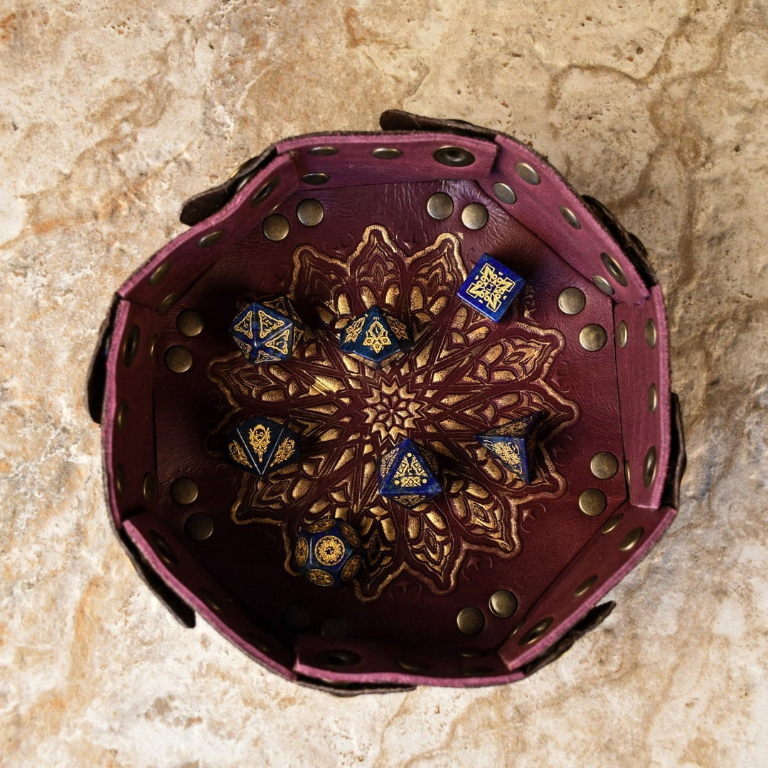 A set of hand-carved blue lapis stone dice with golden patterns, displayed on a Moroccan dnd dice tray