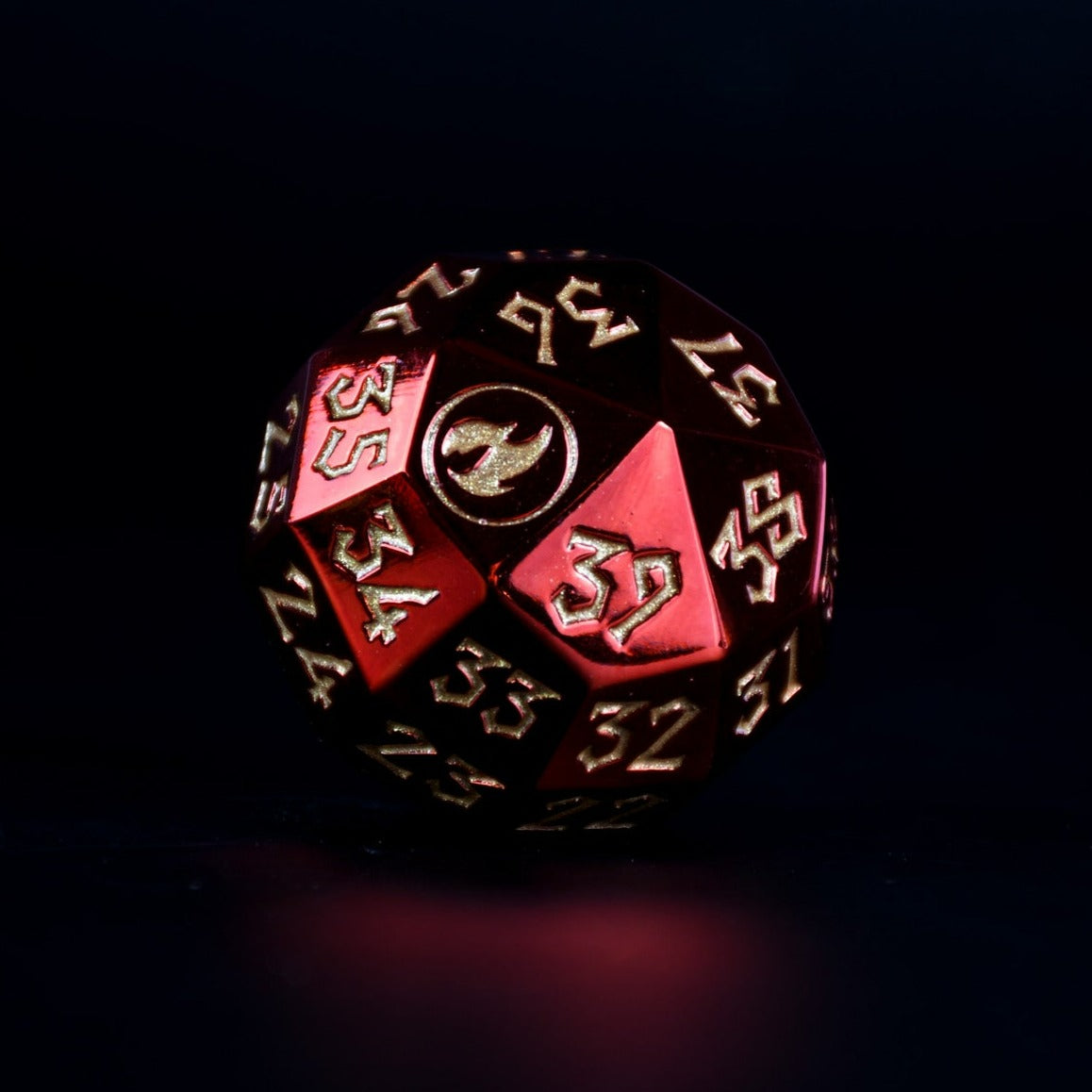A single red metal spindown d40 dice with engraved numbers and a symbol on one face, placed on a wooden surface.