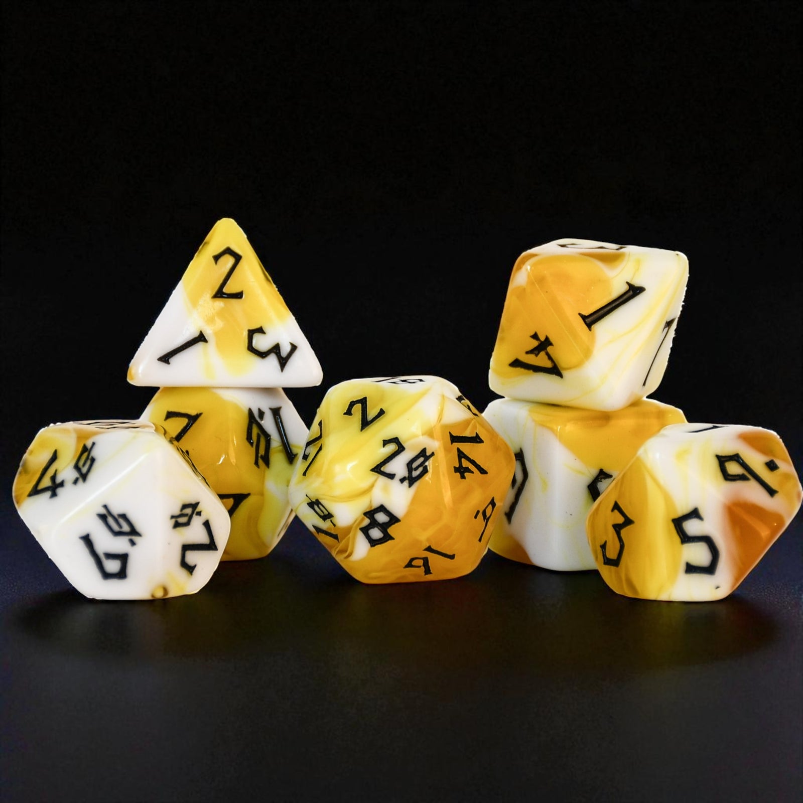 Set of yellow and white polyhedral dice acrylic dice with black numbers inspired by popcorn on a black background
