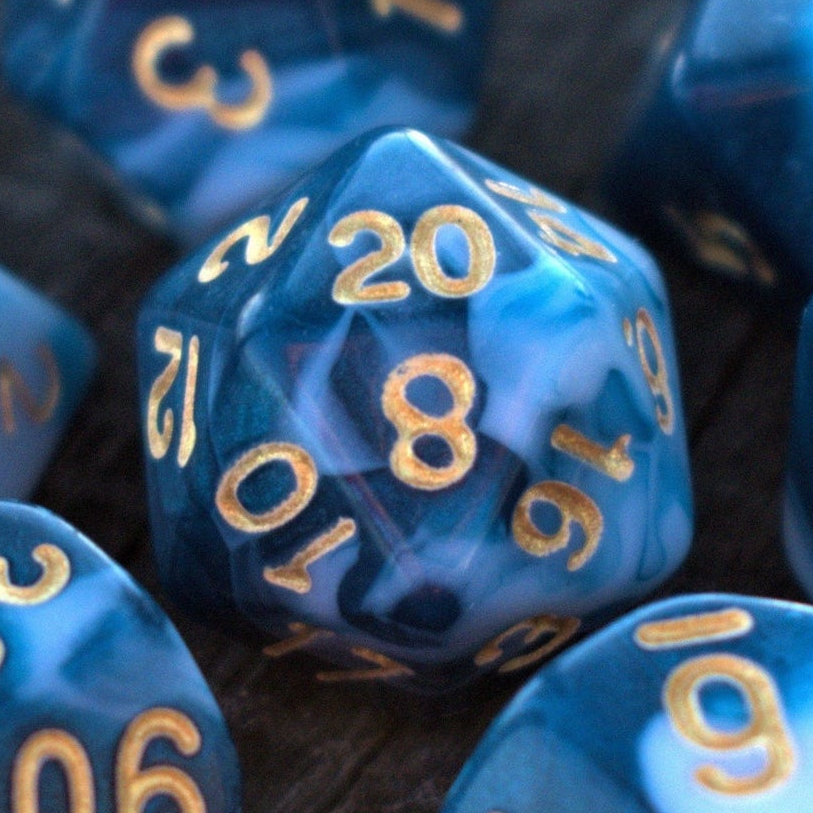 Close-up of blue polyhedral dice with gold numbers on a dark surface