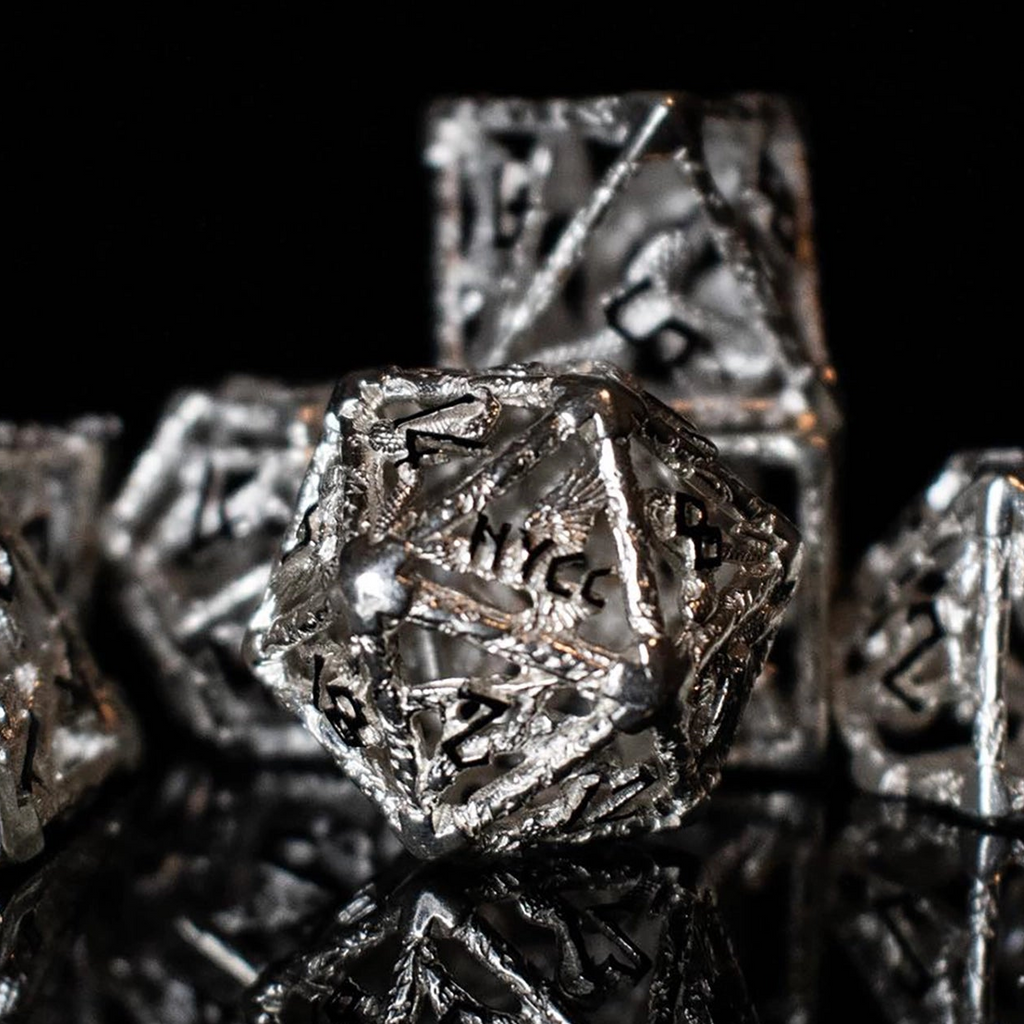 Close-up of metallic polyhedral hollow dice with 'NYCC' branding on a black background