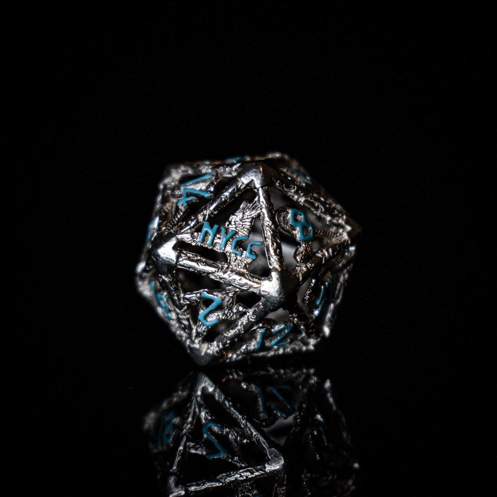 A set of sterling silver hollow dice with embossed numbers, displayed on a reflective surface.