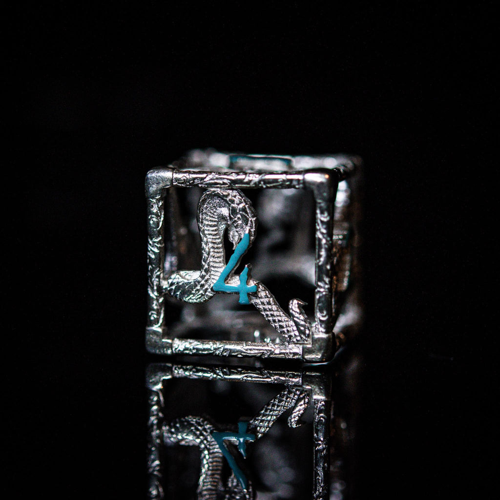 A set of sterling silver hollow dice with embossed numbers, displayed on a reflective surface.