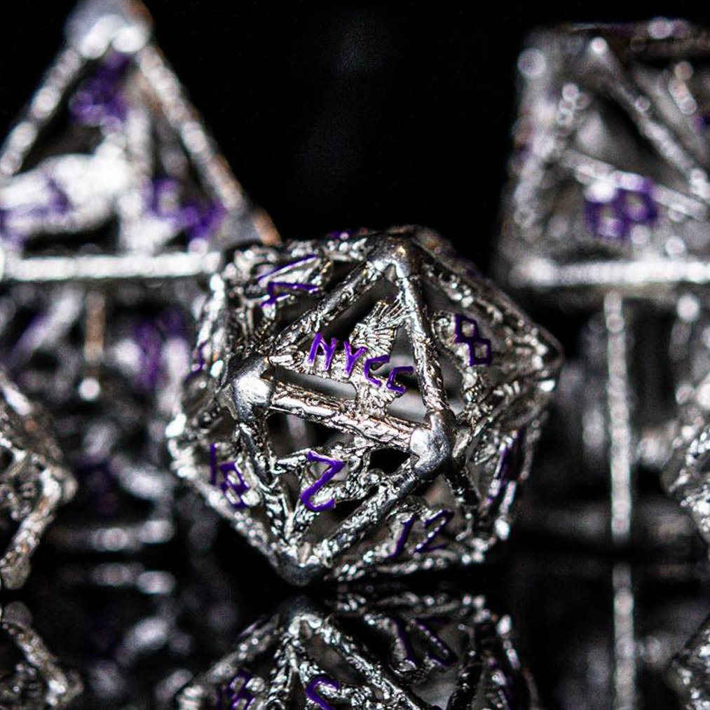 A set of sterling silver hollow dice with purple embossed numbers, displayed on a reflective surface.