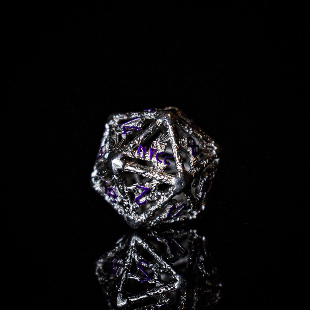 A set of sterling silver hollow dice with purple embossed numbers, displayed on a reflective surface.
