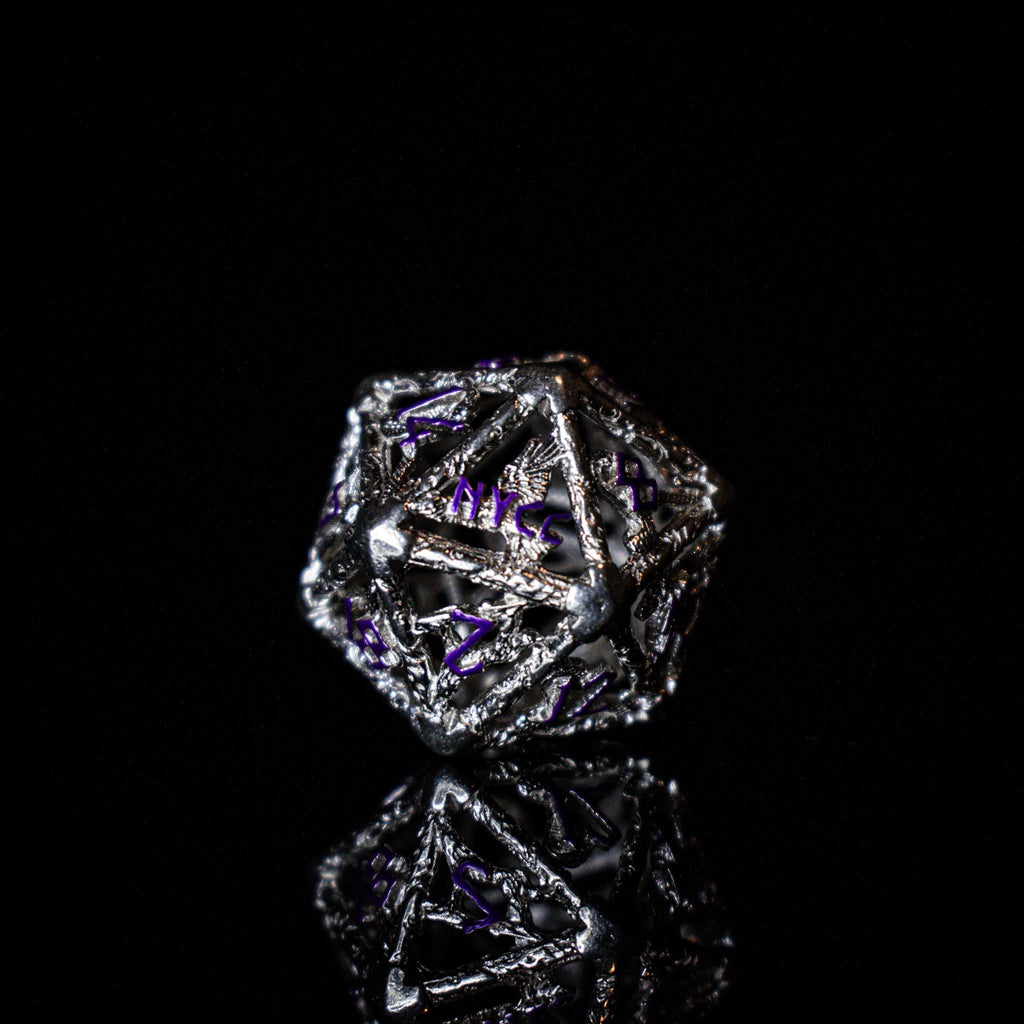 A set of sterling silver hollow dice with purple embossed numbers, displayed on a reflective surface.