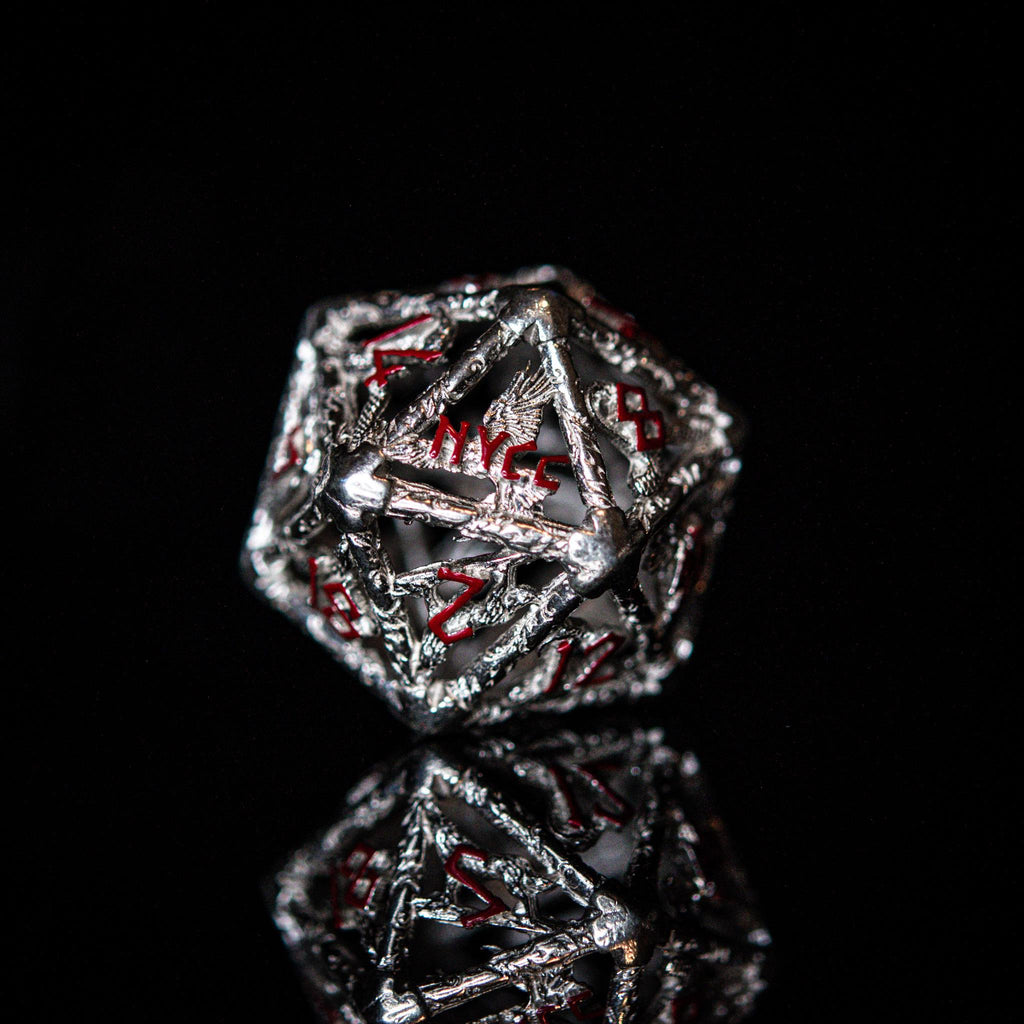 A set of sterling silver dice with red embossed numbers, displayed on a reflective surface.