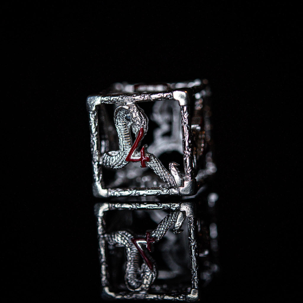 A set of sterling silver dice with red embossed numbers, displayed on a reflective surface.