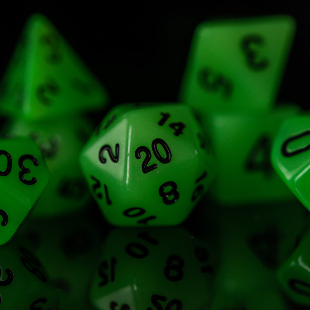 A set of neon green acrylic polyhedral dice with black numbers, including various shapes typical for role-playing games.