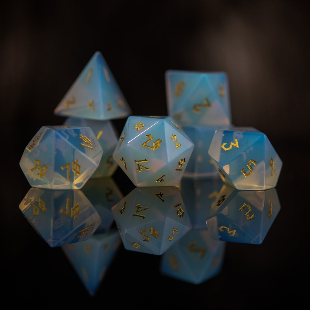 A collection of hand-carved, opalescent white gemstone dice with engraved numbers, displayed against a black background.