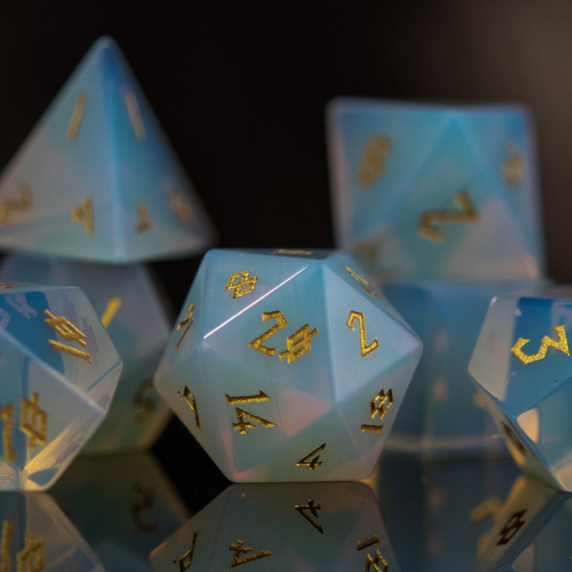 A collection of hand-carved, opalescent white gemstone dice with engraved numbers, displayed against a black background.
