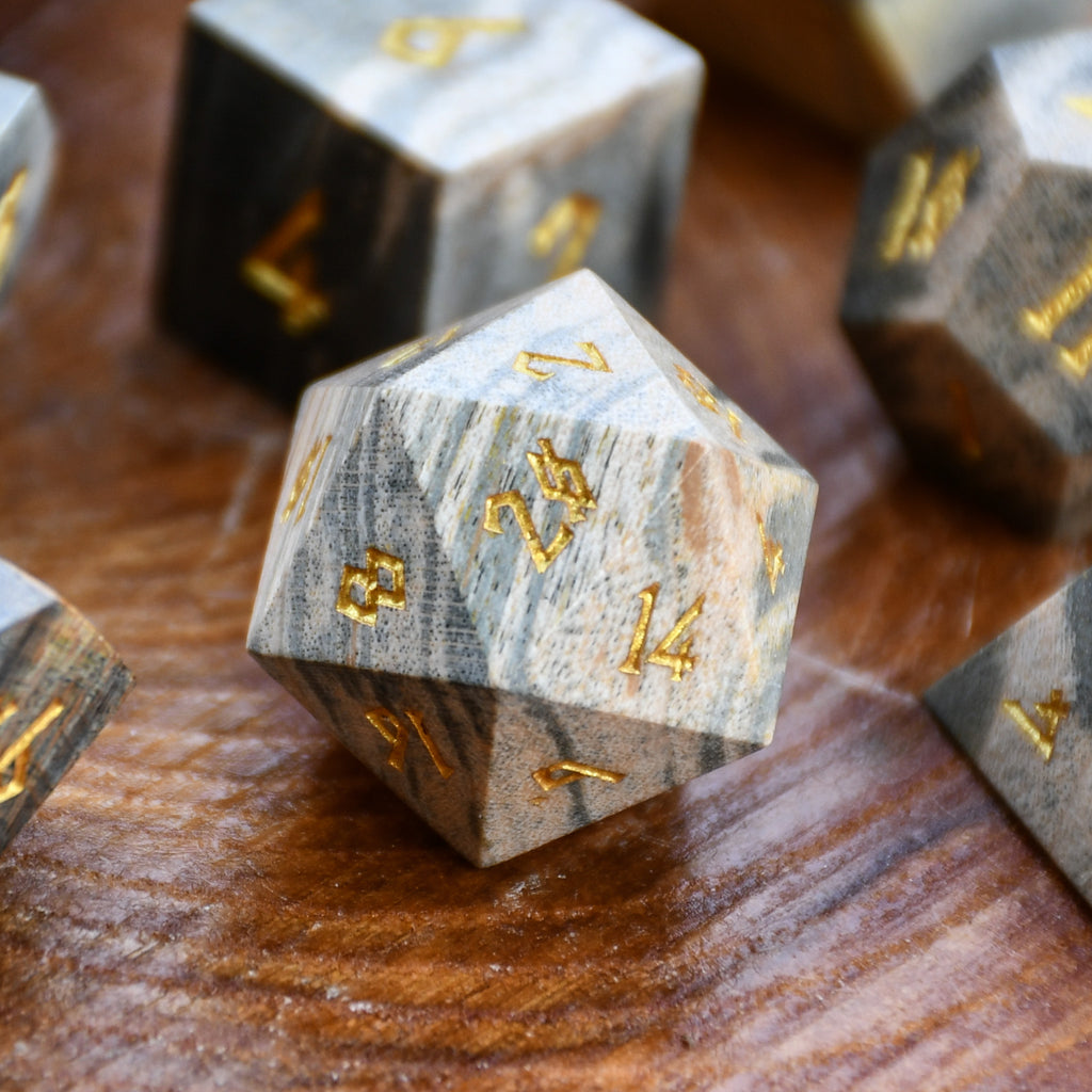 Marble-textured polyhedral wood dice with gold numbers on a wooden surface