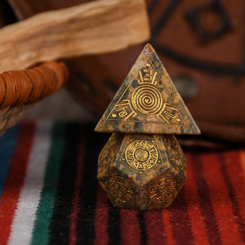 A set of hand-carved Peruvian Leopard Jasper stone dice, featuring engraved patterns and numbers, displayed on a colorful fabric.