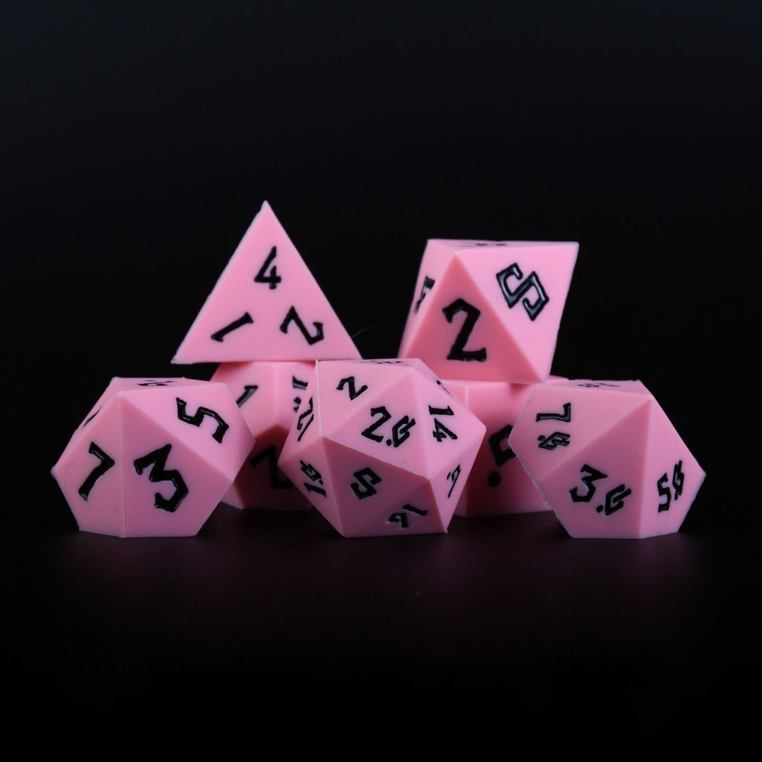 A set of pink silicone dice with black numbering, including various shapes typical for role-playing games.