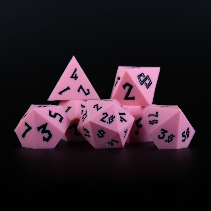 A set of pink silicone dice with black numbering, including various shapes typical for role-playing games.