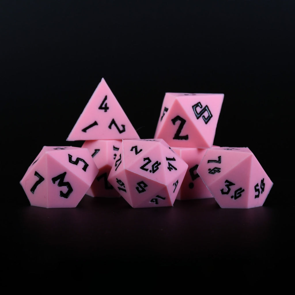A set of pink silicone dice with black numbering, including various shapes typical for role-playing games.