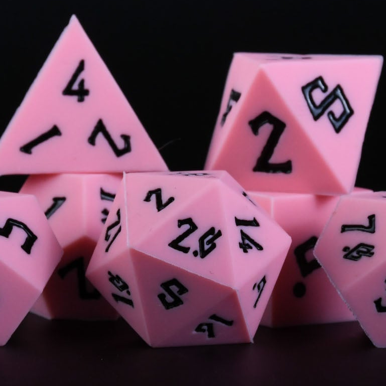 A set of pink silicone dice with black numbering, including various shapes typical for role-playing games.
