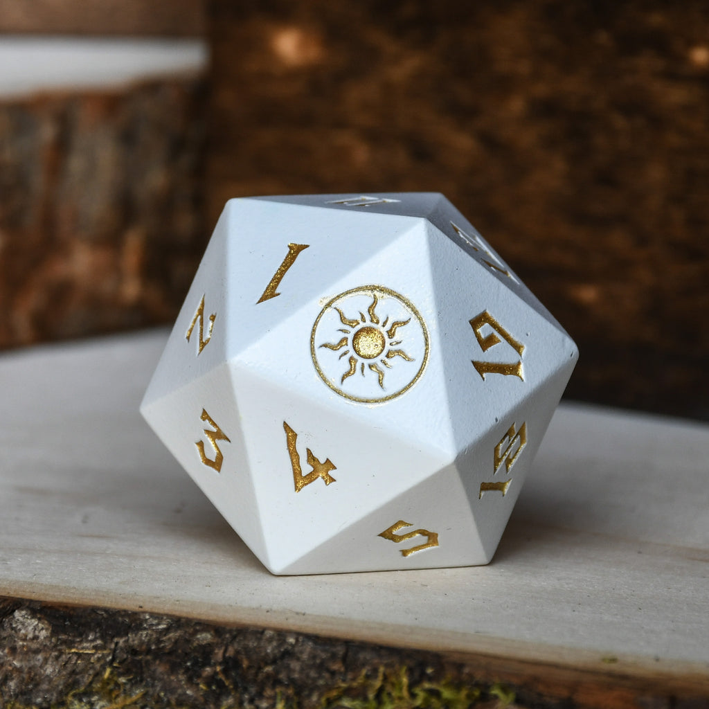 A solid-metal spindown life counter d20 dice, predominantly white with gold details, displayed on a wooden surface.